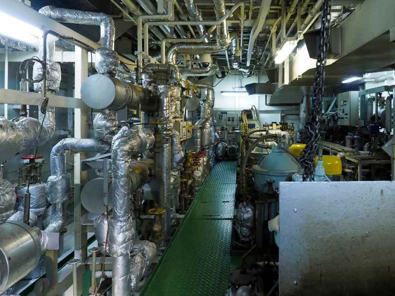 Sala de máquinas con tuberías aisladas y equipos industriales para gestionar consumo energético en una planta.