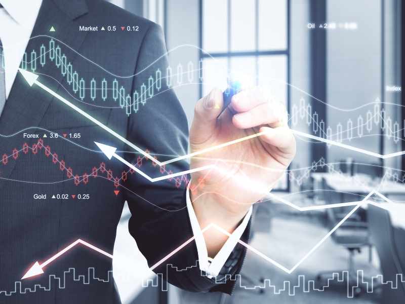 Mano de un profesional dibujando una flecha de crecimiento ascendente sobre una interfaz virtual de datos bursátiles, ilustrando el potencial del apalancamiento financiero.