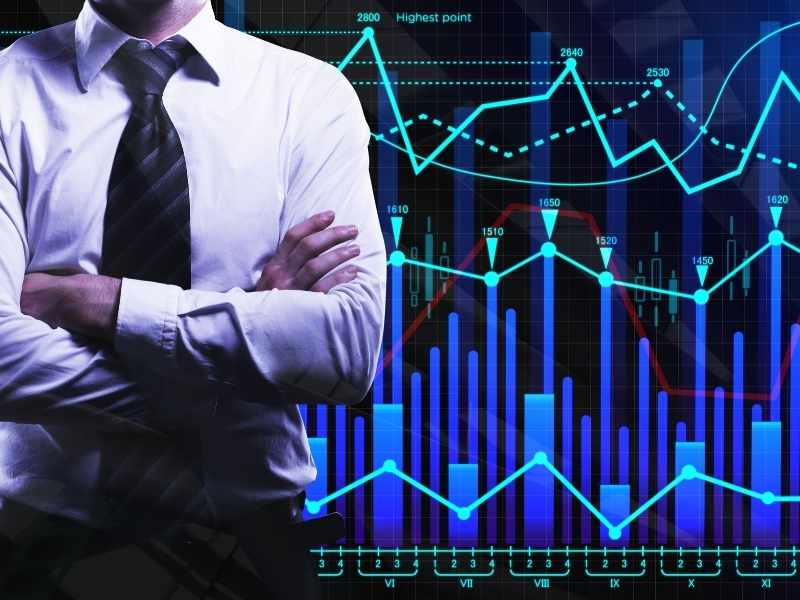 Un ejecutivo de perfil con los brazos cruzados frente a un panel digital de gráficas financieras azules, simbolizando la solidez y visión estratégica en la estructura de capital.