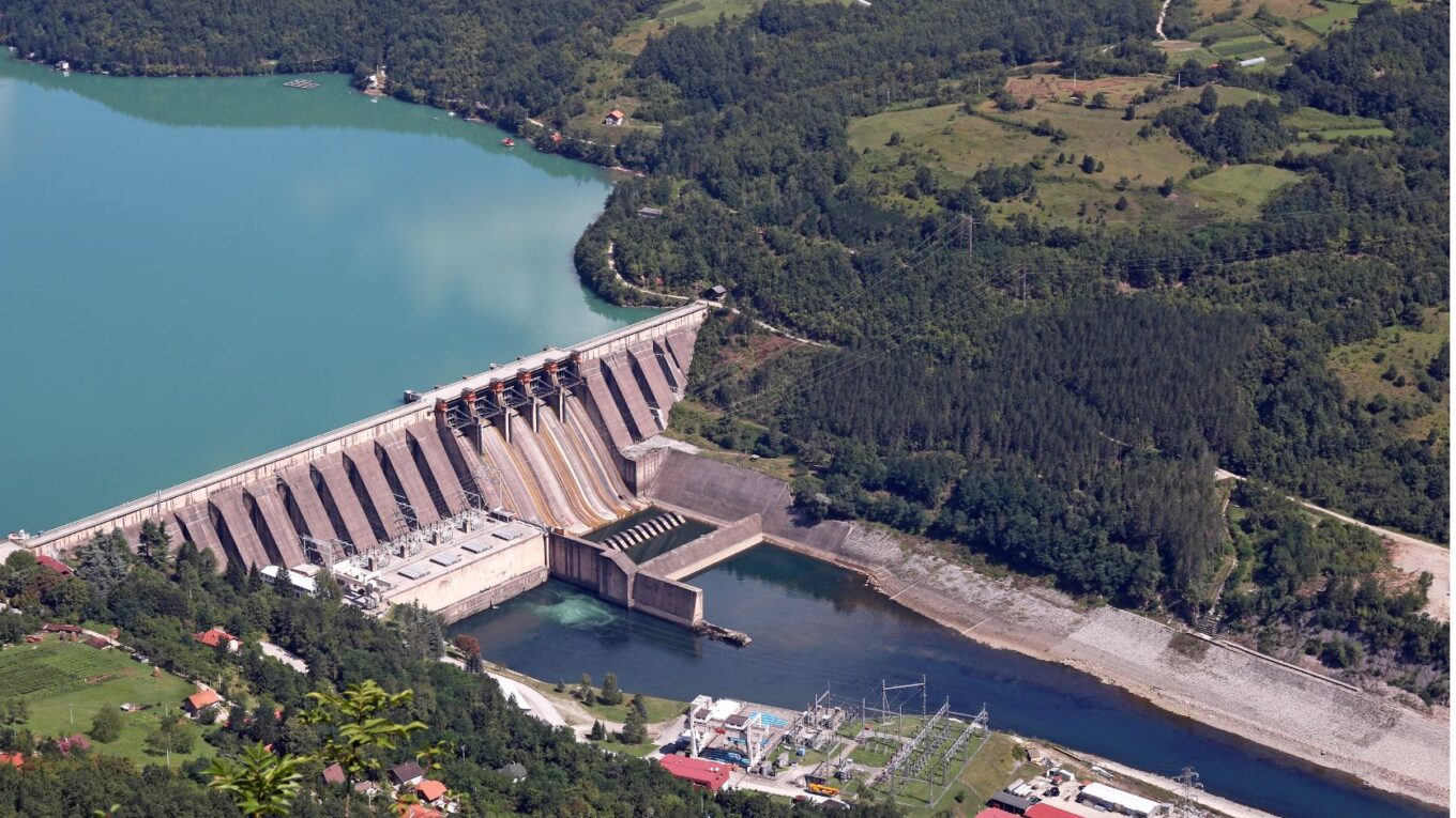Vista aérea de una presa hidroeléctrica rodeada de montañas y un embalse de agua.